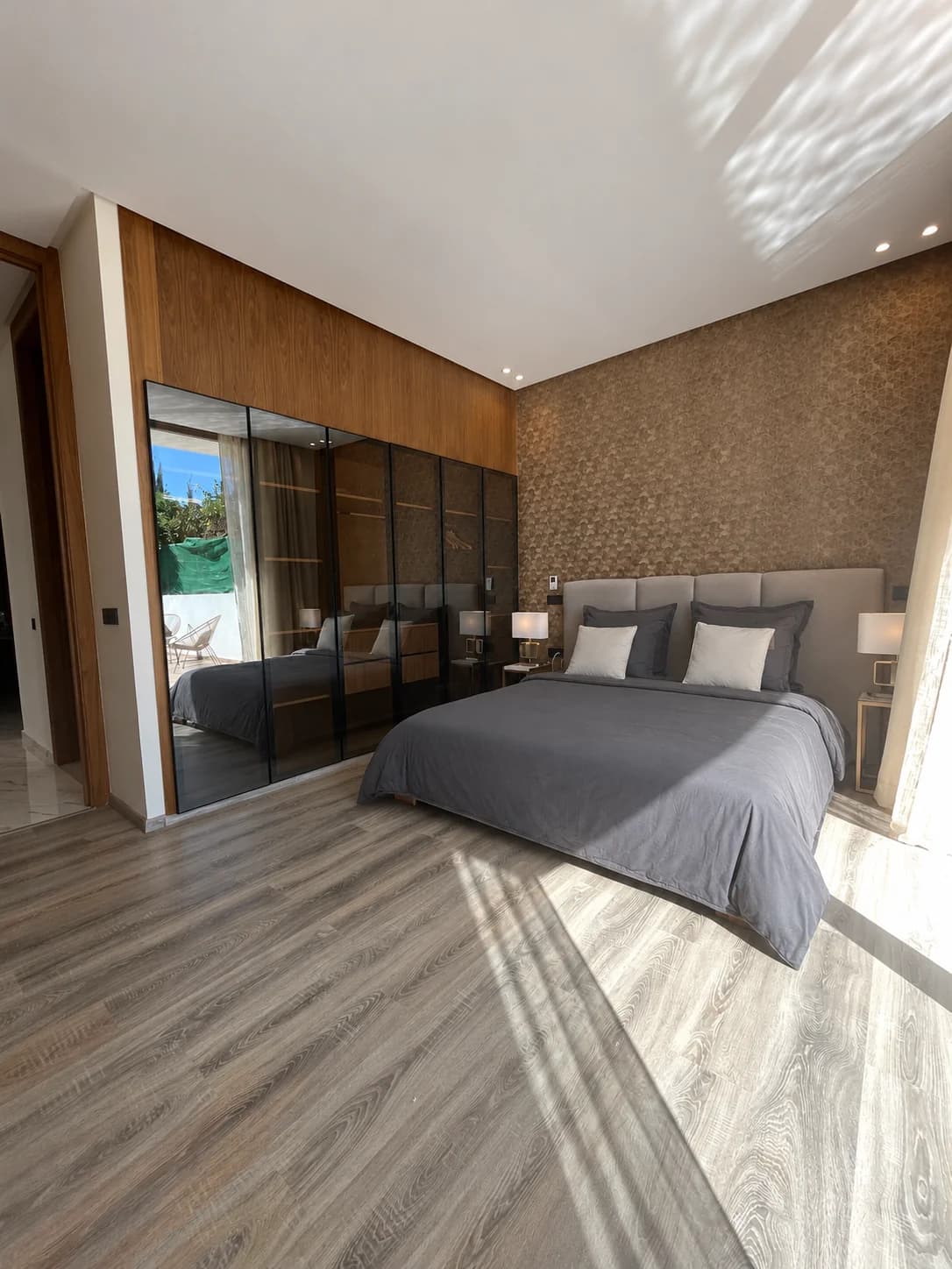 Chambre 1 de la Villa LEANA avec lit double, linge gris et grande armoire vitrée.