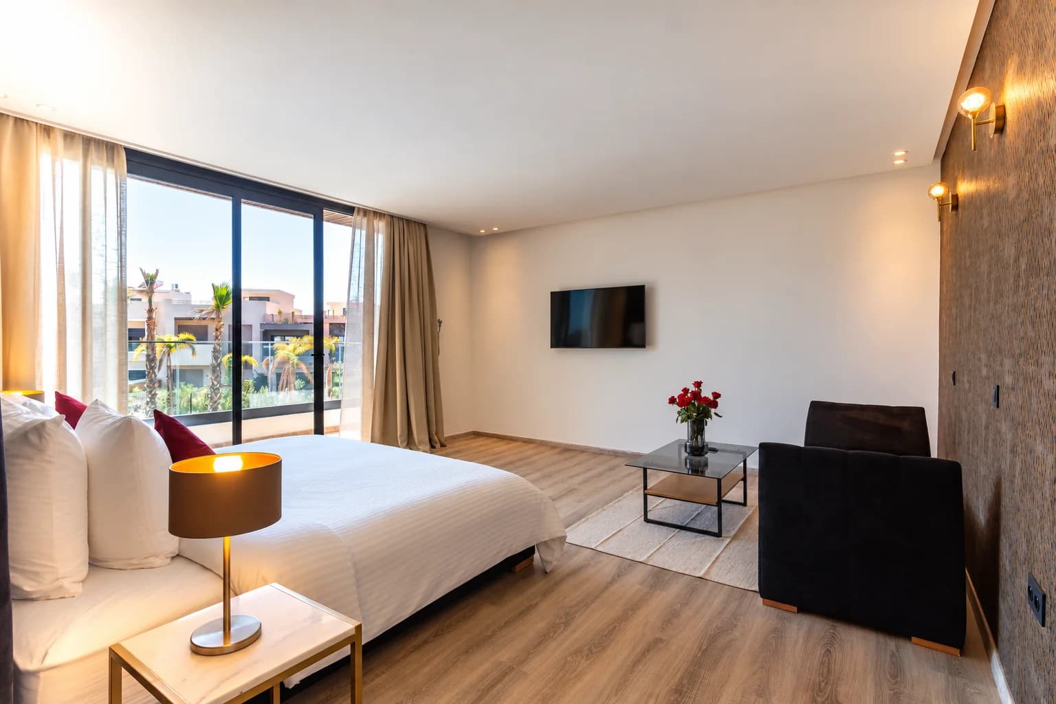 Autre vue de la chambre 2 de la Villa LEANA, avec lit double, fauteuil, télévision et balcon.