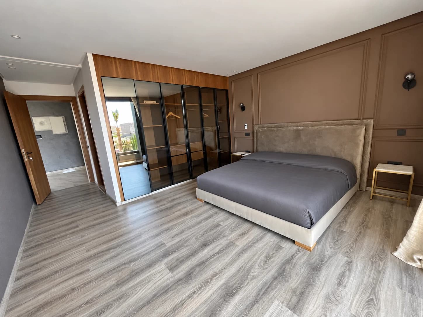 Chambre 3 de la Villa LEANA avec lit double, linge gris, mur taupe et armoire vitrée.