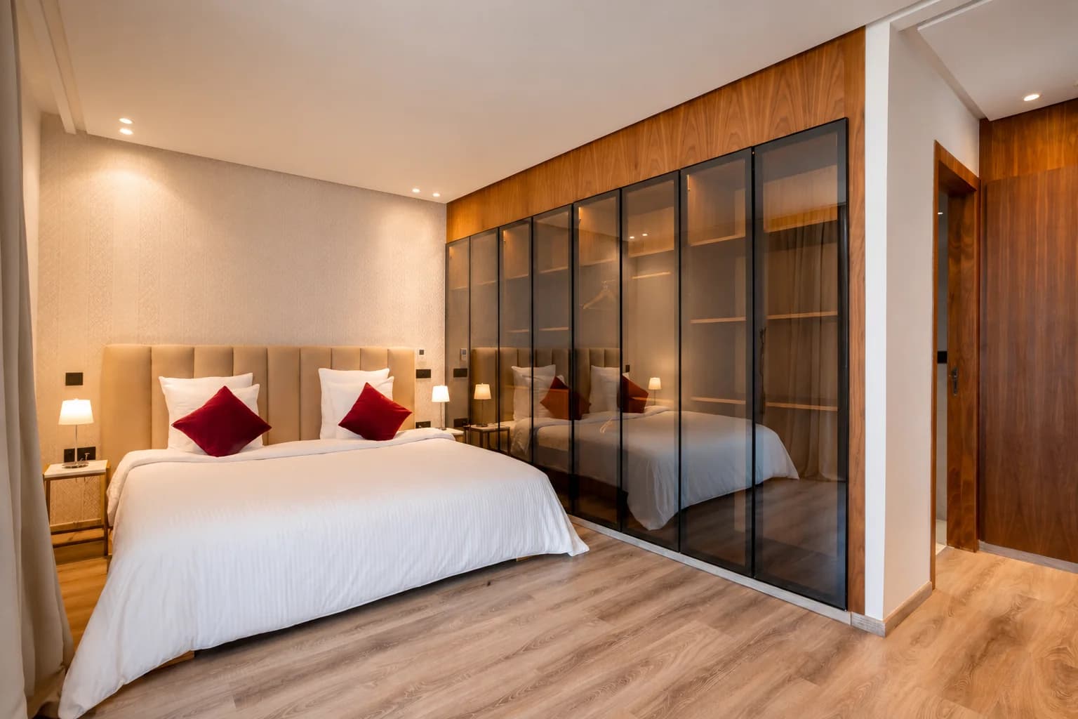 Chambre 4 de la Villa LEANA avec lit double, linge blanc, coussins rouges et armoire vitrée.