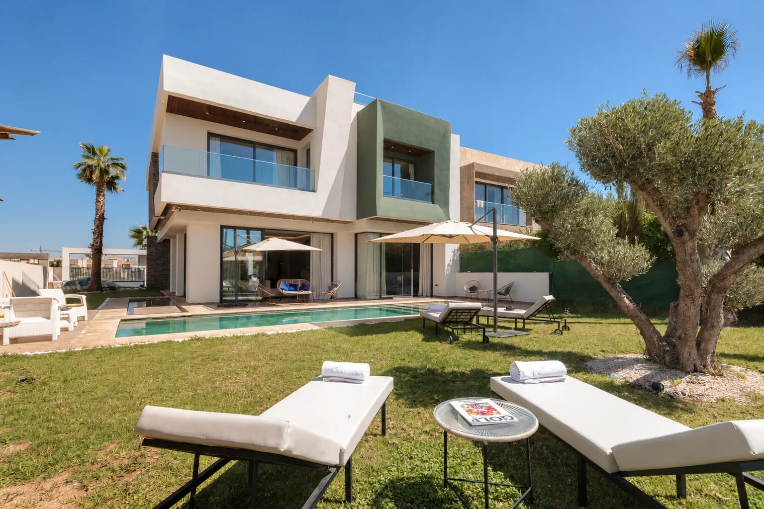 Façade de la Villa LEANA avec piscine, jardin, olivier et transats.